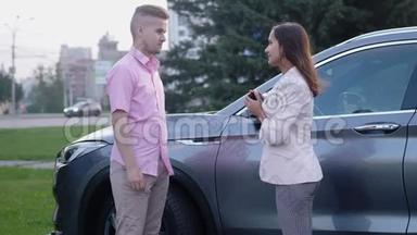 商务女士在汽车背景上收到汽车钥匙。 <strong>商业</strong>人士握手。 成功的交易