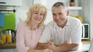 幸福的一对夫妇在现代厨房摆姿势拍照。