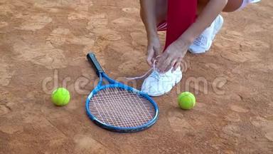 网球运动员在网<strong>球场</strong>上系鞋带. 球拍和两个网球躺在<strong>球场</strong>上
