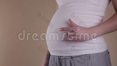 特写腹部孕妇做摇滚符号.. 在家抱着肚子怀孕。 母亲观念。 婴儿淋浴器