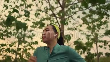 慢速跟踪万向节拍摄年轻健康的亚裔韩国妇女在日落时分在树林中跑步做慢跑锻炼