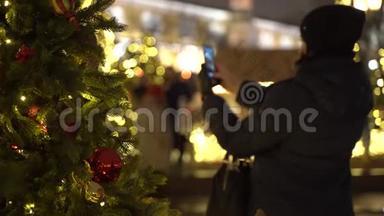 无法辨认的女孩在圣诞树上拍照。 透过新年树`景色