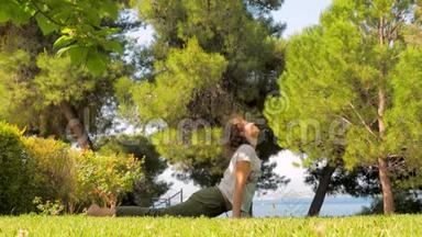 中年妇女在绿草上做<strong>瑜伽</strong>。 活泼的女人在<strong>海边</strong>的绿草上做早操。 <strong>瑜伽</strong>