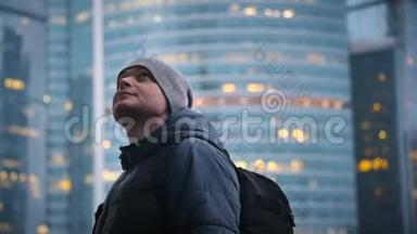 一个带着背包和帽子的年轻人抬头看着摩天大楼起火的背景
