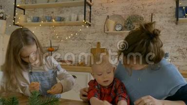 年轻的卷曲妈妈和她的儿子和女儿正在<strong>家中</strong>烹饪圣诞饼干，用圣诞装饰。