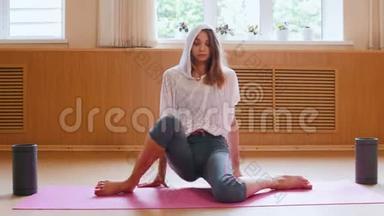 年轻苗条的女人坐在瑜伽垫上，<strong>双</strong>膝并拢，<strong>双</strong>手拉起