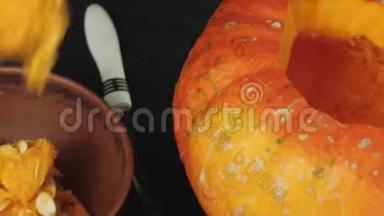 准备在万圣节制作灯笼。 用手在木桌上从一个橙色南瓜中舀取<strong>百事可乐</strong>种子。