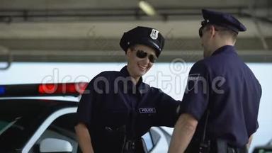 女<strong>警察</strong>和她的伴侣说话，笑着站在巡逻车附近，打破了