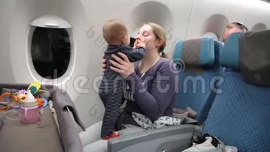 妈妈带着一个快乐的小孩子在飞机上，一个女人把婴儿抱在怀里，拥抱和亲吻她。