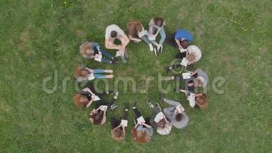 一群学生坐在一个圆圈里，在草地上看书。