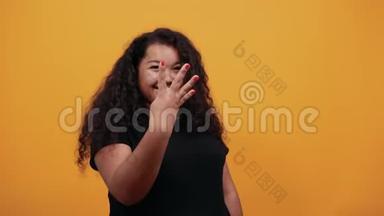迷人的非洲裔美国妇女在橙色墙上镜头前露出三根手指
