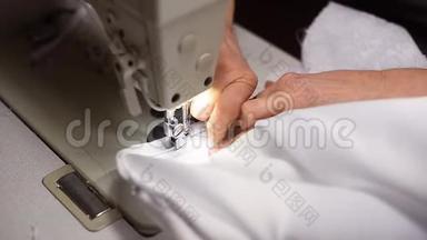 用内置五金灯在缝纫机上点燃白色连衣裙上的手缝拉链。 切断线。 顶角