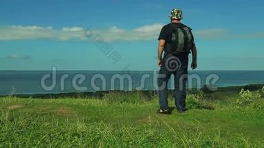 背着背包的人站在山的边缘，欣赏着湖的景色。 射击射击
