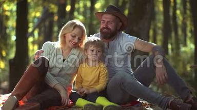 有男孩子的幸福家庭。 年轻的父母和孩子在一个阳光明媚的秋天一起野餐和放松
