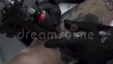 一个纹身艺术家的特写在一个男人`腿上纹身。 很高的分辨率。 专业纹身师在工作室工作。 特写v