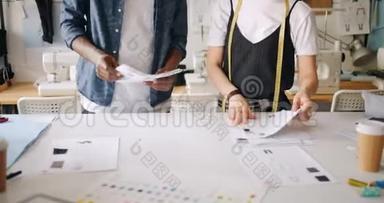 设计服装的人在画草图，桌上摆着纸
