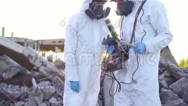 两名穿着防护服和面罩的科学家对个人<strong>电离</strong>辐射剂量计进行了测量