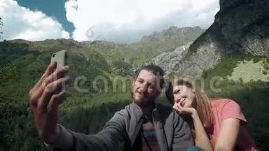 快乐的一对旅人在山上的男人和女人在智能手机上自拍。 为社交网络拍照