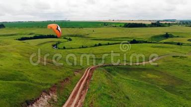 一个拿着滑翔伞的人在空中飞行。 草甸之上的滑翔伞..