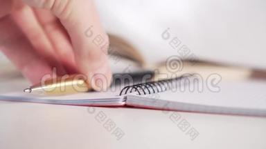 一个年轻人把一支金色的笔放在一个理财师身上，桌子上有黑色的螺旋页，背景是一本书