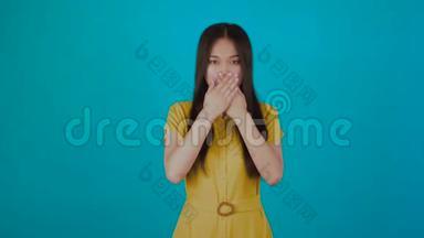 亚洲女孩闭上嘴，双手示意。 孤立在蓝色背景上。 社会问题概念