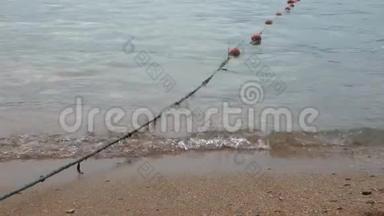 小浪在沙滩上冲浪。 有漂浮物的长绳进入水中