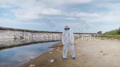 一个穿着防护服和呼吸器的人站在塑料垃圾桶中，靠近一条干涸的河流，挥动他的手