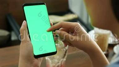 4K. 女士在咖啡店使用带有空白绿色屏幕模型的移动智能手机，使用手指触摸屏幕和幻灯片，滑动。