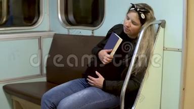 一位孕妇在地铁火车上手里拿着一本书睡着了。 旧地铁列车