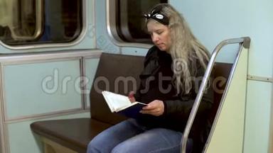 一位孕妇正在地铁火车上看书。 旧地铁列车