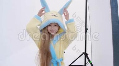 无法辨认的女人在拍摄白色背景的照片时，用兔子浴袍给可爱的女孩拍照