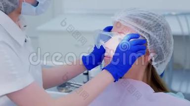 牙医在牙科治疗牙齿前给病人戴上防护眼镜。