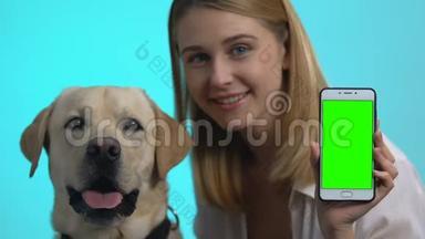 快乐狗主人展示智能手机绿色屏幕，可爱的宠物看相机，应用程序