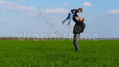 一个快乐的孩子穿过绿草，跑到父亲的怀里，父亲把孩子抱在怀里，把他扔出去