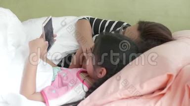 母亲和女儿女孩在卧室里<strong>玩手机</strong>。