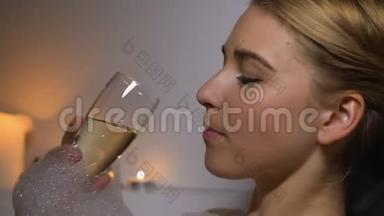 平静的女人在沐浴中享受晚间水疗，泡沫，喝香槟，放松