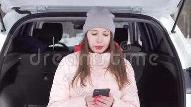 穿着灰色帽子和粉<strong>红色</strong>夹克的漂亮女孩开着白色的车来到<strong>冬季</strong>公园
