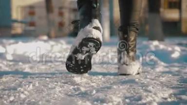 女足穿黑色靴子，冬天走在雪地里。 在冬季公园散步的女人的腿。