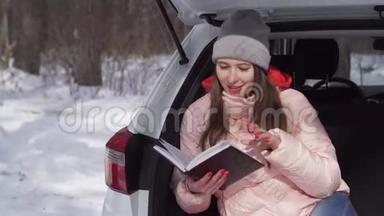 美丽的女孩坐在白色的车里，在针叶林中<strong>翻阅</strong>日记