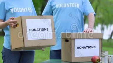 两名志愿者手持捐款箱，人道主义使命，慈善理念，帮助