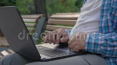 公园里老人用电脑的特写镜头。他正在触摸触摸板浏览互联网