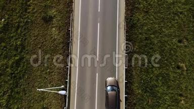 鸟瞰孤独的棕色SUV汽车在两片田野之间的道路上行驶。 两条车道的路上有车。
