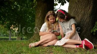 两个小女生用智能手机。 孩子们在玩，看书，看电话。 人、儿童、技术