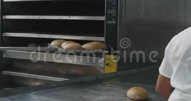 面包业烘焙面包从烤箱中取出，面包师厨师他协助安排面包上的特殊面包。