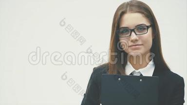 这位商务女士站在白色的背景上。 它拿着一个带有文件的黑色文件夹，仔细看着相机。