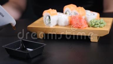 食物录像。 酱油倒入黑色背景的盘子里。 将寿司摆放在木板上很漂亮。 日本