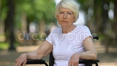 坐在轮椅上的悲伤女人深深地叹了<strong>口气</strong>，坐在户外，残疾，特写