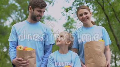 快乐的<strong>志愿者</strong>家庭带着苹果纸袋，微笑的相机，慈善机构