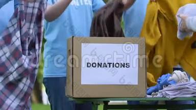 志愿者小组把衣服放进捐赠箱，孤儿院慈善项目帮助