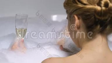 迷人的女人在带泡沫的浴缸里<strong>享受</strong>香槟，<strong>享受</strong>奢华的放松